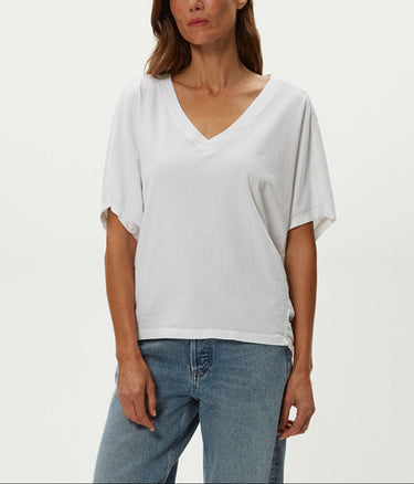 Woman wearing a white oversized t-shirt and blue jeans on a plain background