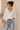 Woman wearing a white blouse and blue jeans against a neutral background