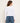 A woman wearing a white long sleeve and blue jeans facing backwards on a white background