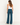 A woman wearing teal ribbed foldover pants, a white tank and sneakers on a white background.