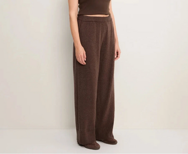 A woman wearing brown knit pants on a white background