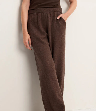 A woman wearing brown knit pants on a white background