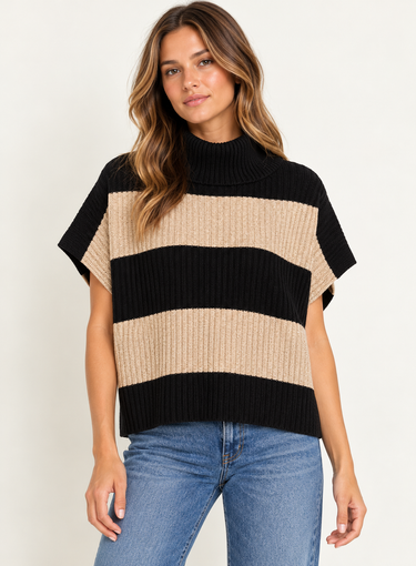 A woman wearing a beige and black stripe turtleneck poncho vest and blue jeans on a white background.