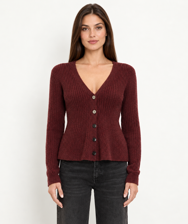 a woman wearing a burgundy ribbed v-neck cardigan and blue jeans on a white background.