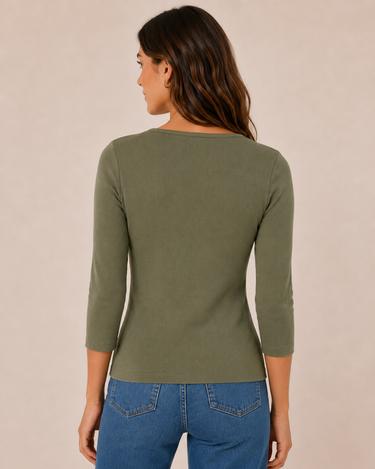 A woman viewed from the back wearing a fitted olive green three-quarter sleeve top and blue jeans against a plain beige studio background.