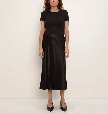 a woman wearing a black tee and a black bias midi skirt on a white background.