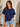 Woman wearing a blue t-shirt and denim shorts indoors.