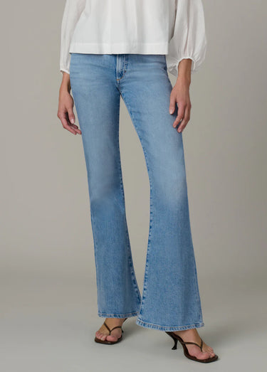 Person wearing light blue flared jeans on a neutral background