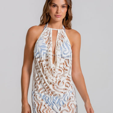 Woman wearing a patterned halter neck dress on a plain background