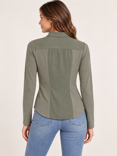 A woman shown from the back wearing a long-sleeve collared blouse in a muted sage green color, paired with light blue jeans, against a plain off-white studio background.