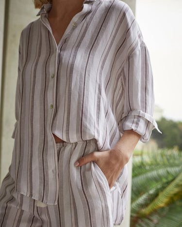 Person wearing a striped shirt and pants with a blurred natural background