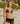A woman wearing a black bikini under sheer lace shorts on a beach.