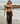 A woman wearing black lace sheer cover up pants over a black bikini on a beach.