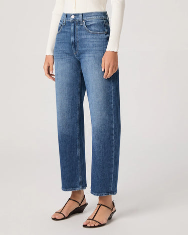 Person wearing blue jeans on a plain background