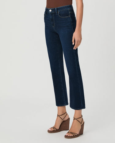 A model wearing dark blue cropped straight-leg jeans with brown wedge sandals, shown from the waist down against a light gray studio background.