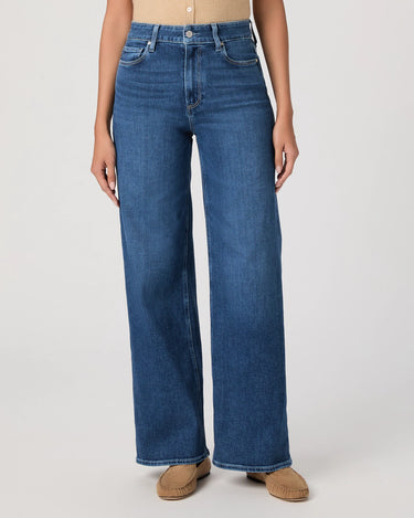 Person wearing blue jeans on a plain background