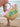 Woven beach bag with pink and green accents held by a person on a sandy beach.
