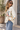 A woman wearing oversized white jacket with “Peace” written across the front and Blue jeans on An outside background
