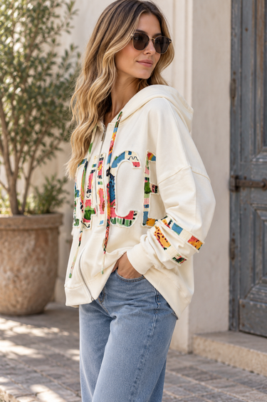 A woman wearing oversized white jacket with “Peace” written across the front and Blue jeans on An outside background
