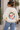 a woman wearing a white oversized hoodie with a colorful peace sign on the back