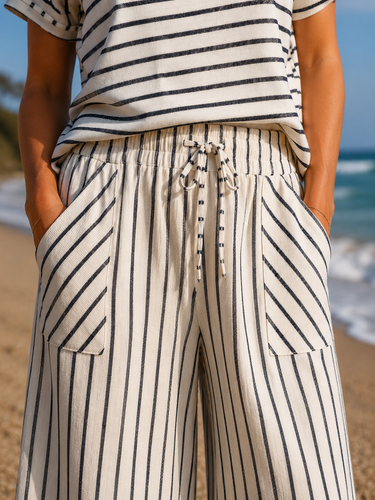 Person wearing a striped shirt and pants with a blurred beach background
