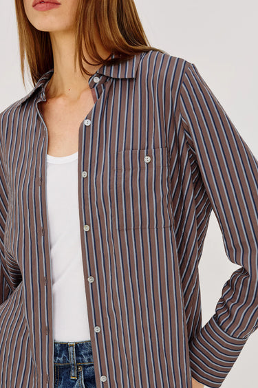 Woman wearing a striped shirt over a white top with a neutral background
