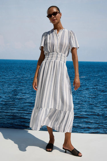 Woman in a striped dress standing by the ocean