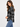 a woman wearing a black and ivory plaid collared shirt and blue jeans on a white background.