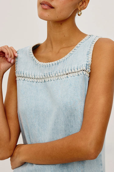 Light blue denim top worn by a person on a plain background