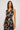 Woman wearing a sleeveless dress with a leaf pattern on a plain background