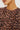 Close-up of a person wearing a fuzzy knit top with a leopard print pattern in brown and black on a dusty pink background.