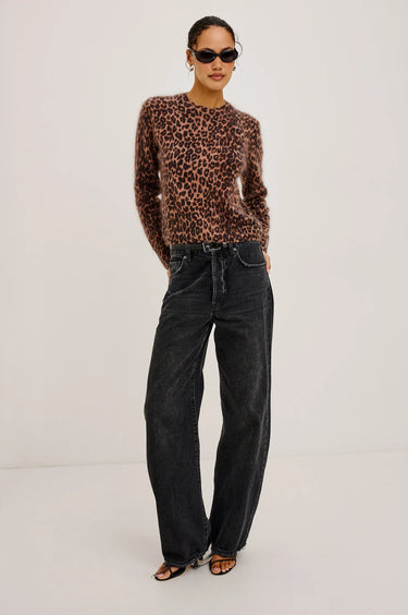 Person wearing a leopard print sweater and black jeans on a white background