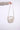A cream-colored faux fur shoulder bag with a matching fabric strap, held by a person's hand wearing a matching cream sleeve against a plain white background.