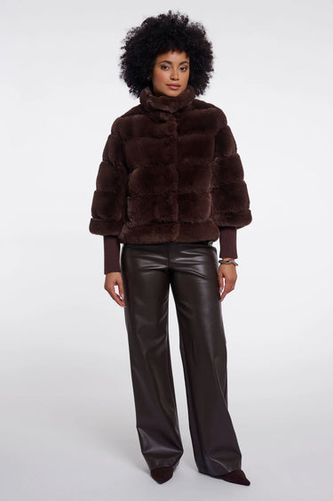Woman wearing a brown fur coat and black leather pants on a white background
