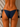 Navy blue bikini bottom with gold accents on a beige background