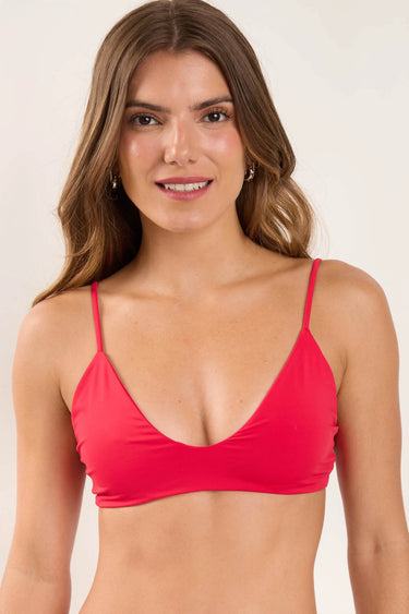 Woman wearing a red bikini top against a plain background