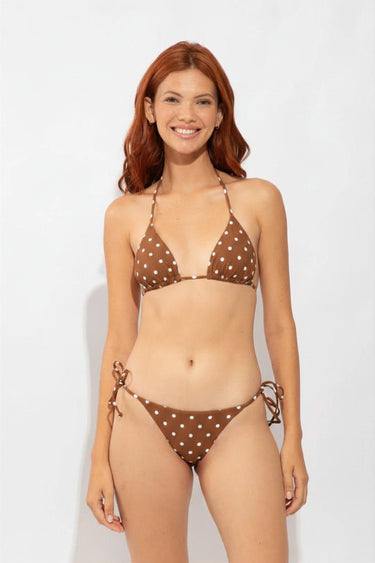Woman wearing a brown polka dot bikini against a white background
