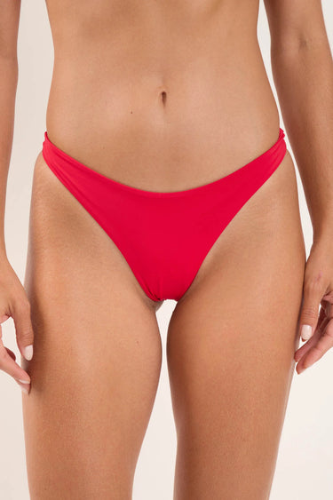 a woman wearing a red bikini bottom on a neutral background