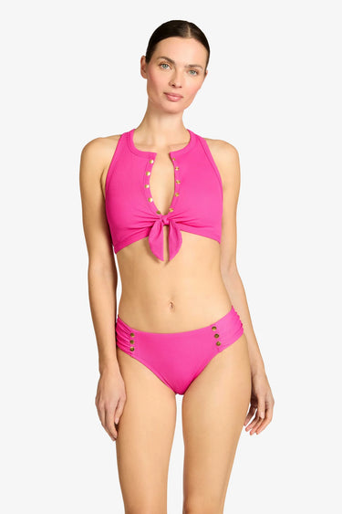 Woman wearing a pink bikini with gold buttons on a white background