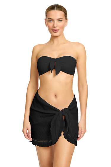 Woman wearing a black strapless top and black shorts on a white background