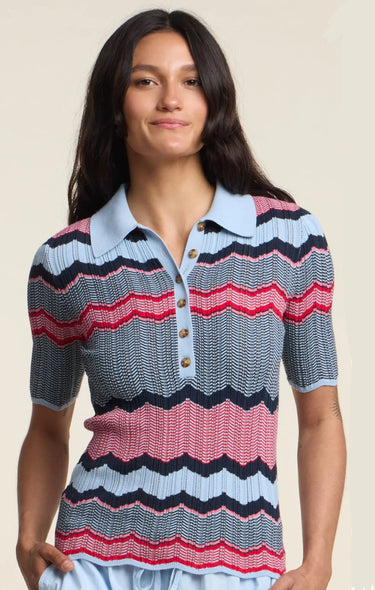 Woman wearing a colorful striped polo shirt against a beige background