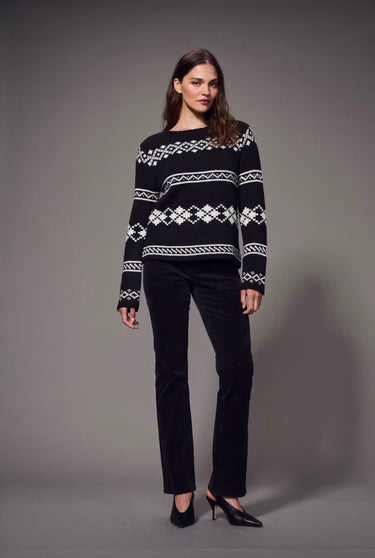 Black and white Fair Isle patterned sweater styled with slim black pants and black heels on a model.