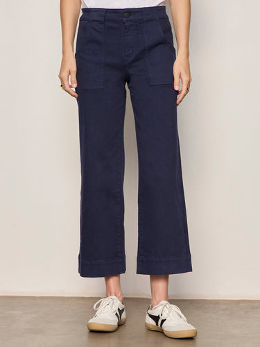 A woman wearing navy blue cropped pants on a neutral background