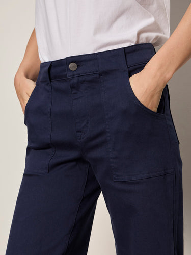 A woman wearing navy blue cropped pants on a neutral background