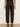 Rear view of a model wearing dark brown wide-leg trousers with a high waist, cuffed ankles, and side cargo pockets, paired with black high-heeled sandals.