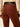 Rear view of a person wearing brown corduroy pants with a black belt, paired with a cream lace long-sleeve top, against a light beige background.