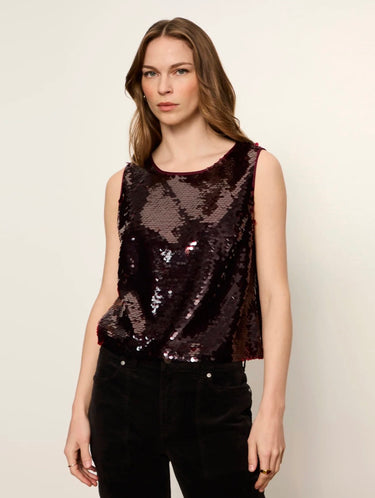 A woman modeling a sleeveless, dark burgundy sequined crop top paired with black pants, set against a plain off-white studio background.