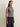 Model wearing a navy and ivory striped sleeveless knit sweater with navy pinstripe wide-leg pants.