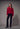 a woman wearing a brushed v-neck red sweater and black jeans on a grey studio background.