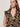 A close-up of a model wearing a sleeveless V-neck blouse with a beige and black paisley pattern, set against a plain light gray background.